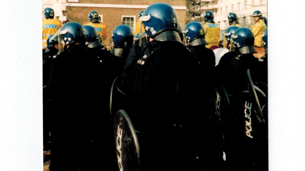 Picture of police in riot gear carrying shields and wearing helmets.